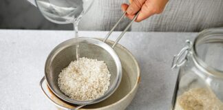 Why the ‘Ricezempic’ Trend Can Be Dangerous, According to Experts A close-up of a person holding a small silver colander filled with rice over a beige ceramic bowl while pouring water over the rice.