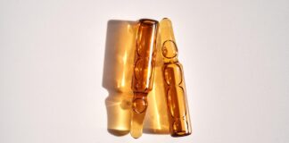 Sunshine in a Capsule: Vitamin D Supplements Explained and Who Should Take Them Two brown-colored vitamin D ampoules and their reflections on a white background.