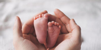Supporting new moms: why postpartum nutrition matters A mother gently holds her newborn’s tiny feet, highlighting the importance of proper nutrition and care for moms during the “fourth trimester.” Shutterstock photo.