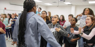 Students share ideas on mental health supports during Sources of Strength Peer Leader Summit – Kentucky Teacher A large group of student should out guesses to a student who is acting out a phrase.