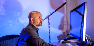 Why is it So Hard for Autistic People to Get Mental Health? Matthew Goodwin sitting at a desk working on a computer.