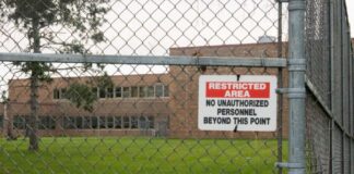 Expanded Anoka mental health hospital could reduce use of jails A building is seen through a fence, with a sign reading "Restricted Area: No unauthorized personnel beyond this point" in the foreground, and a man mowing the lawn in front of the building