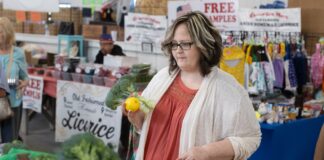 A fresh start: Penn State Health’s Veggie Rx program offers a recipe for wellness A woman holds a head of broccoli and an orange while looking at other produce at a farmer’s market. She is wearing a sweater and has glasses.