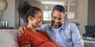 Early-life nutrition | National Institutes of Health (NIH) Pregnant woman on couch with man, both smiling and touching her belly.