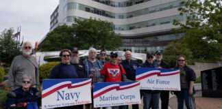 VA’s 6-Service Challenge inspires Veteran wellness A group of people poses in front of a building, holding signs for Navy, Marine Corps, and Air Force, symbolizing a 6-Service Veteran Challenge. for wellness.