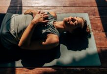 2026 Health and Wellness Trends woman lies on yoga mat in the sun preparing for sleep, representing one of the top 2026 health and wellness trends
