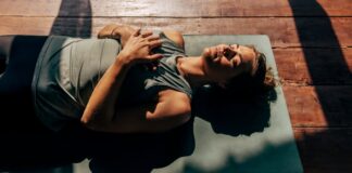 2026 Health and Wellness Trends woman lies on yoga mat in the sun preparing for sleep, representing one of the top 2026 health and wellness trends