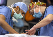 The Medical Minute: Advances in head and neck cancer care bring new hope Two surgeons operate on a patient. The man on the left is wearing a face mask and scrubs. The woman on the right is wearing a colorful surgical cap, glasses, face mask and scrubs.